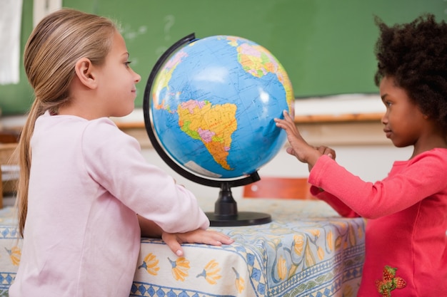 Écolières souriantes en regardant un globe