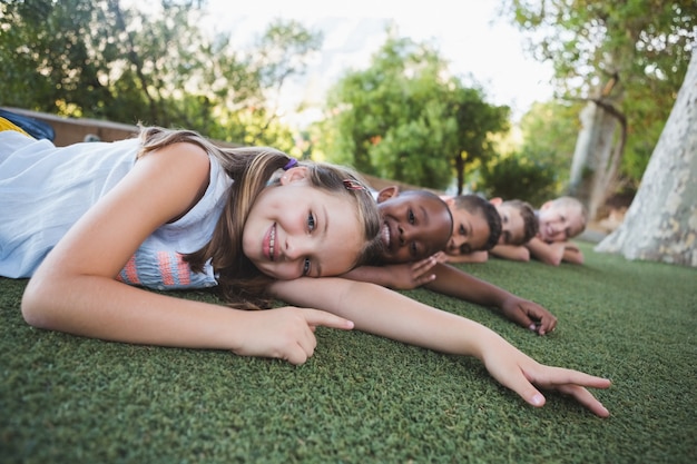 Écoliers souriants couché sur l'herbe dans le campus