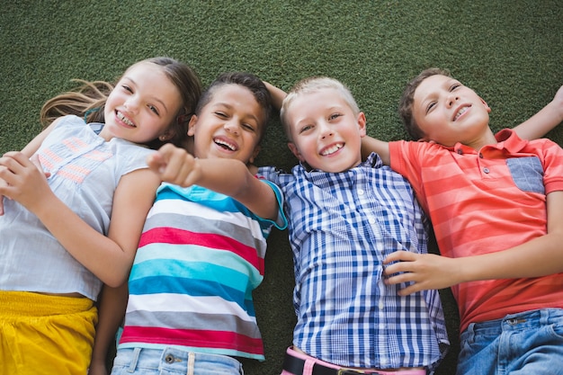 Écoliers souriants couché sur l'herbe dans le campus