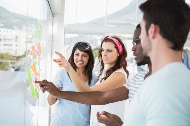 Collaborateurs concentrés pointant des notes autocollantes