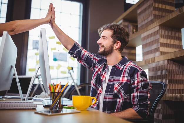 Collaborateurs créatifs high fiving au bureau dans le bureau