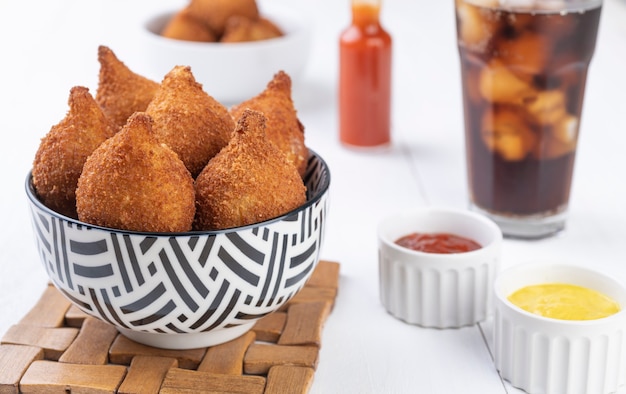 Collation brésilienne typique coxinha sur un bol avec verre de soda.