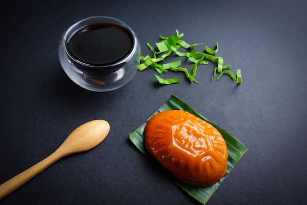 Collation chinoise traditionnelle malaisienne avec une cuillère en bois, un verre de thé noir et une feuille de pandan