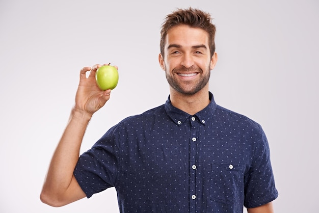 La collation qui garde votre corps heureux Portrait d'un beau jeune homme tenant une pomme et souriant