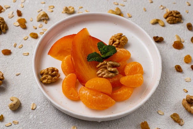 Collation saine fruits, kakis et mandarines aux noix sur un tableau blanc