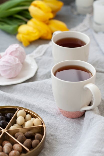 Une collation savoureuse: deux tasses de thé, une assiette de zéphyr et une boîte de bonbons.