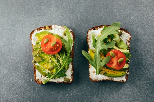 Collation végétalienne saine. Toasts à l'avocat avec fromage cottage, roquette et tomate. Vue de dessus