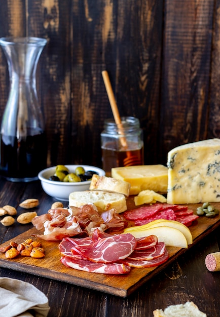 Photo collation de vin. prosciutto, jambon de parme, salami, amandes, olives, baguette, fromage bleu, parmesan. antipasti.