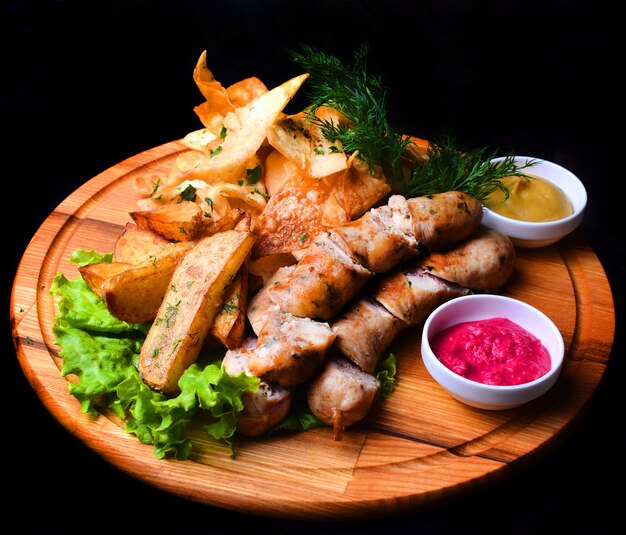 Des collations à la bière sur une planche de bois. Saucisses frites bavaroises, pommes de terre frites, frites isolées