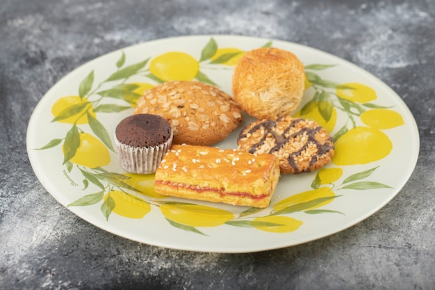 Des collations sucrées dans une assiette posée sur une table en pierre.