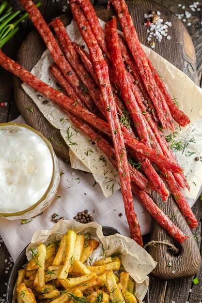 collations de viande pour la bière, à côté d'un verre de bière, frites dans une casserole, sur une table rustique en bois