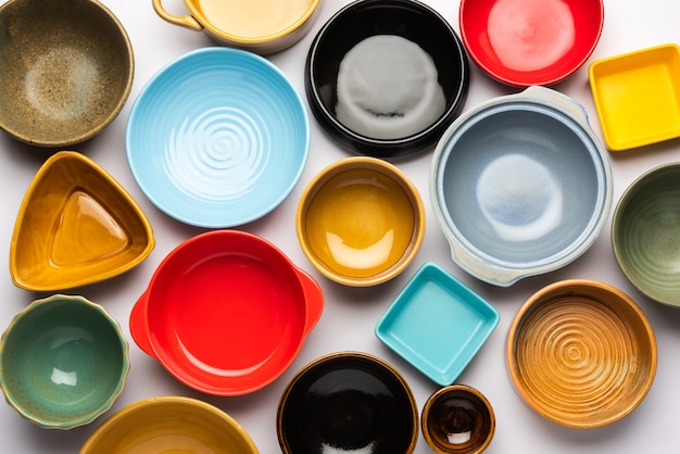 Collection de bols en céramique colorés vides. Groupe d'ustensiles capturés d'en haut, vue de dessus, mise à plat sur fond blanc