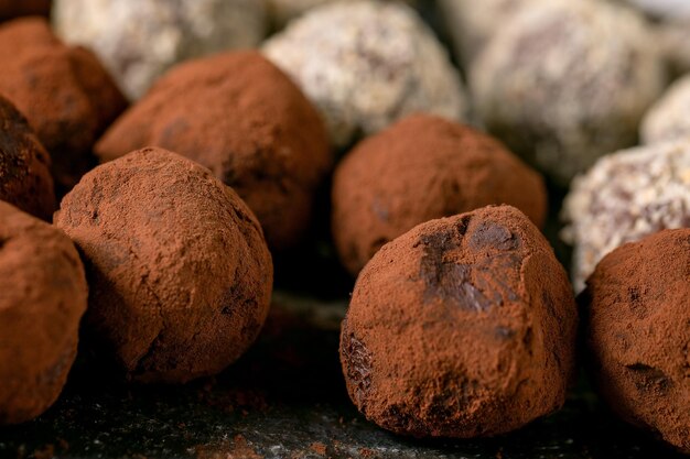 Collection de bonbons à la truffe au chocolat et aux noix faits maison sur une assiette en céramique noire. Cadeaux sucrés faits à la main pour toutes les vacances. Fermer