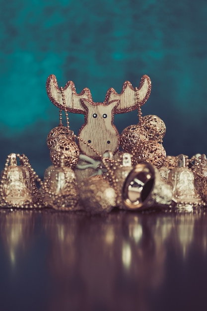 Collection de boules de Noël dorées et ornements de cloche avec des cerfs en bois sur turquoise