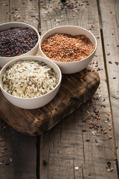 Collection de différentes variétés de riz sur fond rustique en bois.