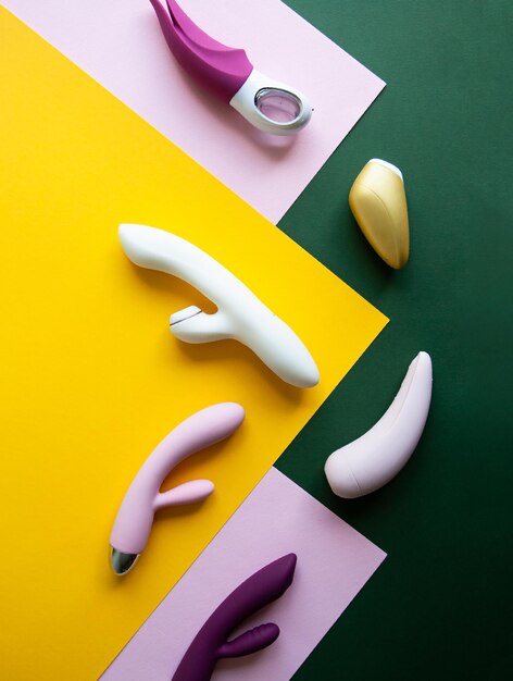 Photo collection de différents types de jouets sexuels sur fond rose vert et jaune