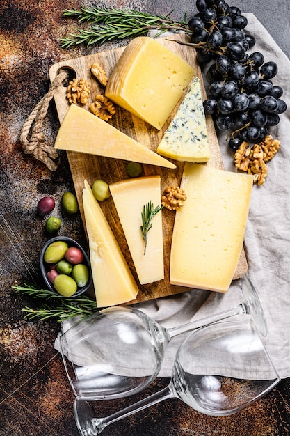 Collection de fromages suisses, hollandais, français, italiens avec noix et raisins. Fond sombre. Vue de dessus