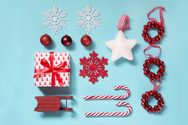 Collection de Noël avec des cannes de bonbon, des boules, un rouge traîneau sur bleu.