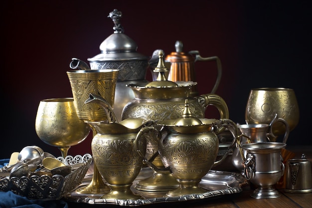 Une collection de vieilles tasses à thé en laiton et d'autres objets sont sur une table.