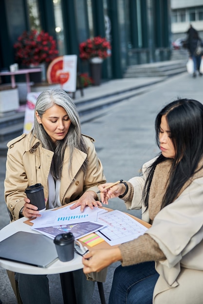 Collègues d'affaires femmes étudiant des documents dans un café en plein air