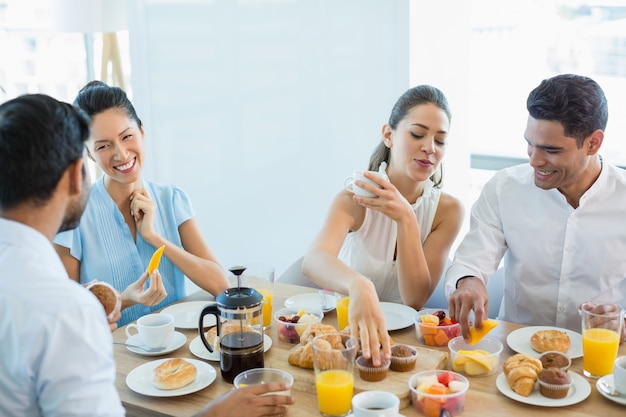 Collègues d'affaires interagissant entre eux tout en prenant le petit déjeuner