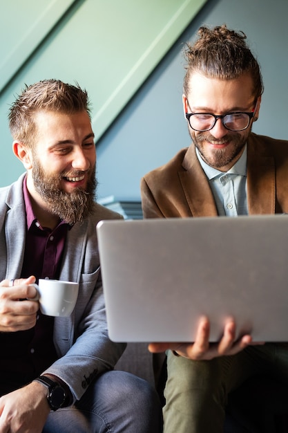 Collègues d'affaires riant, travaillant tout en regardant l'ordinateur portable