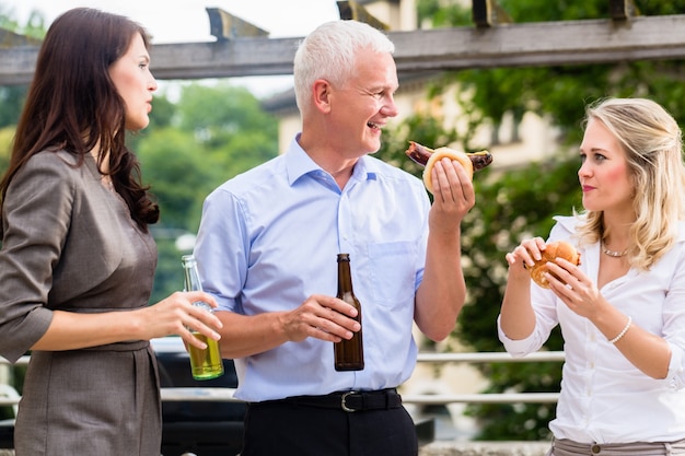 Collègues ayant des saucisses et de la bière après le travail