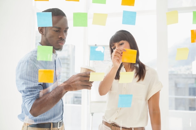 Des collègues concentrés regardant des notes autocollantes