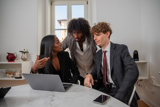 Des collègues discutent au travail à l'aide d'un groupe d'affaires multiethnique pour ordinateur portable