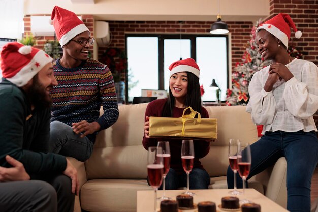 Collègues échangeant des cadeaux de noël lors des fêtes de bureau, buvant du vin et offrant des cadeaux de noël sur le lieu de travail avec des ornements et un décor festifs. Des gens heureux s'amusant lors des fêtes.