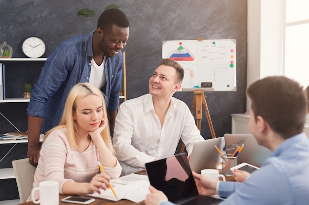 Collègues de l'entreprise discutant d'idées et remue-méninges au bureau, chef d'équipe noir contrôlant le processus, espace de copie