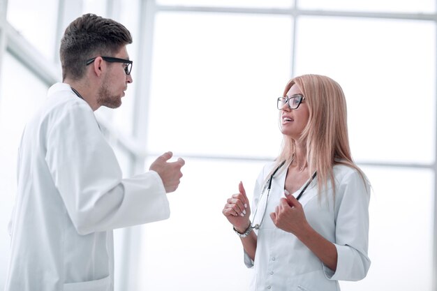 Des collègues médicaux sérieux discutent de quelque chose debout dans le couloir de l'hôpital