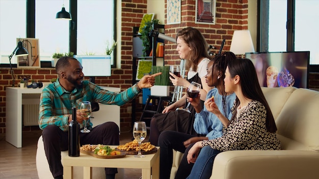 Photo des collègues multiethniques socialisant à la maison en dégustant des boissons alcoolisées