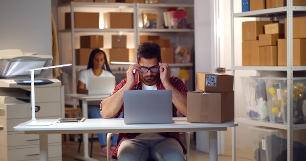 Collègues multiethniques travaillant sur ordinateur portable dans un petit entrepôt