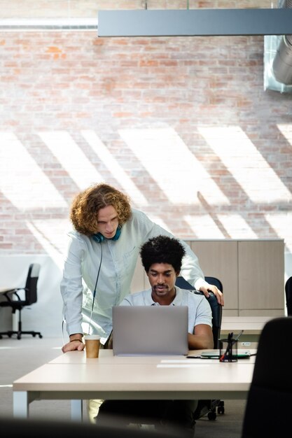 Des collègues multiraciaux regardent ensemble l'ordinateur au bureau. Espace de copie. Image verticale. Concept d'entreprise.