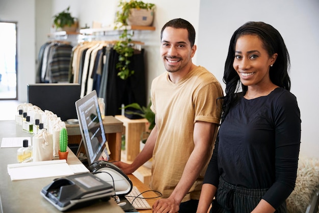 Collègues souriants derrière le comptoir d'un magasin de vêtements