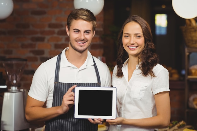 Collègues souriants montrant une tablette