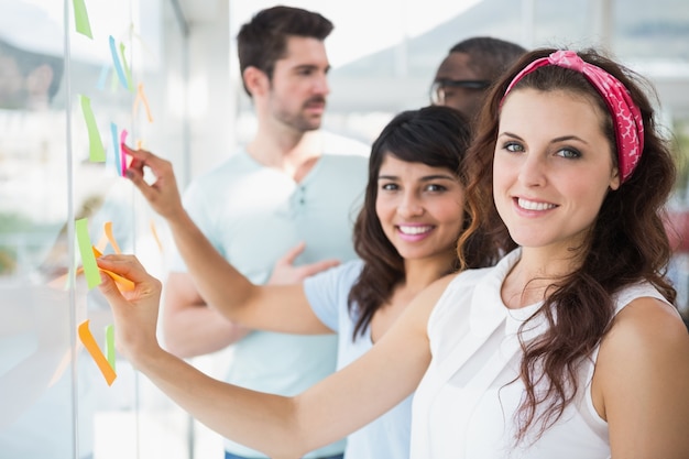 Collègues souriants pointant des notes autocollantes