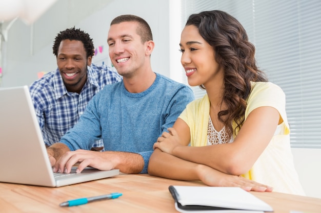 Collègues souriants travaillant ensemble avec un ordinateur portable