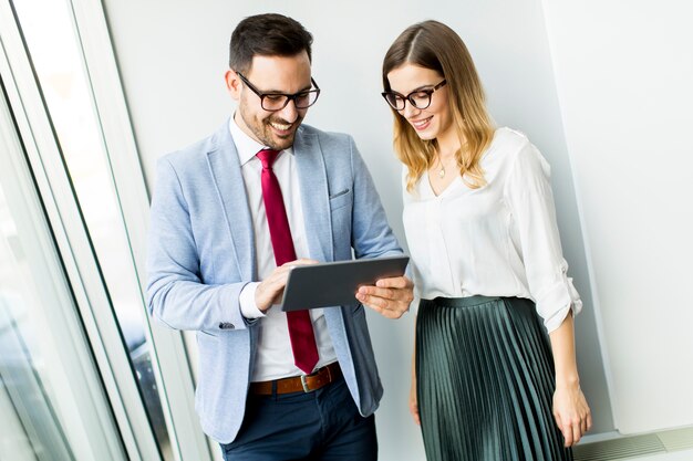 Collègues de travail heureux dans les bureaux modernes avec tablette