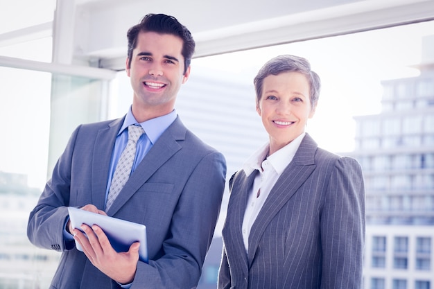 Collègues de travail, souriant à la caméra et tenant la tablette