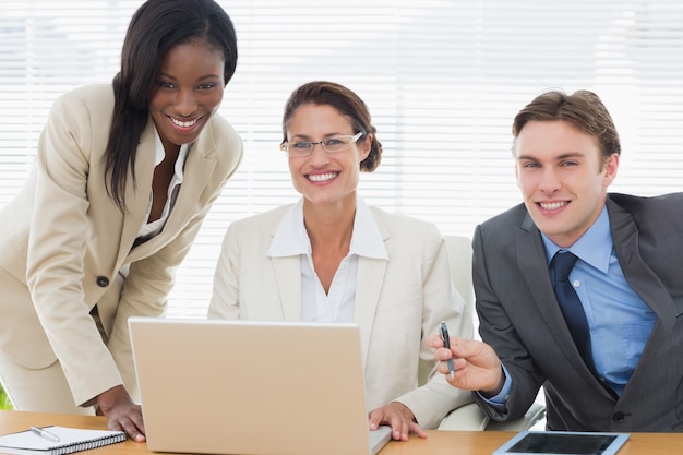 Collègues de travail souriant avec ordinateur portable en réunion