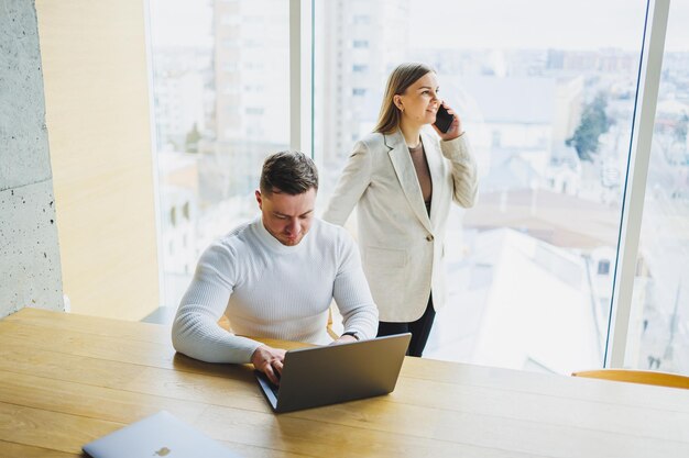 Collègues travaillant avec un ordinateur portable au bureau Deux entrepreneurs axés sur les objectifs collaborent dans un espace de travail moderne Deux jeunes hommes d'affaires travaillent dans un bureau lumineux