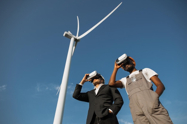 Collègues utilisant des lunettes VR pour travailler à la ferme avec des moulins à vent