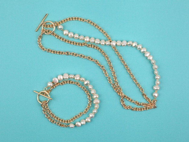 Collier et bracelet de perles baroques élégants de luxe sur fond texturé turquoise vif. Photo en gros plan