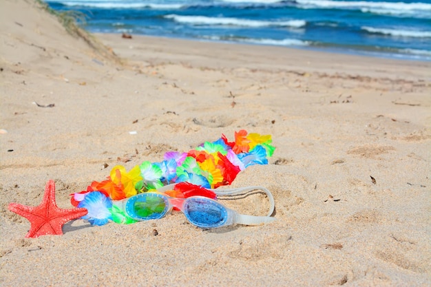 Collier hawaïen et lunettes de plage sur le sable