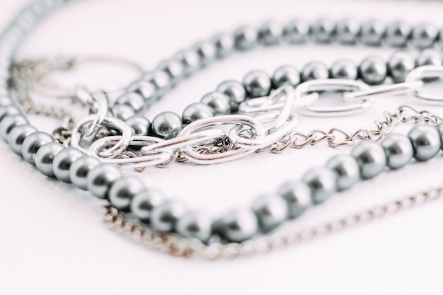 Un collier de perles grises avec des décorations de chaîne sur un fond esthétique blanc