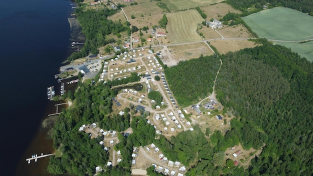 une colline bordée d'arbres verts avec des maisons et un plan d'eau