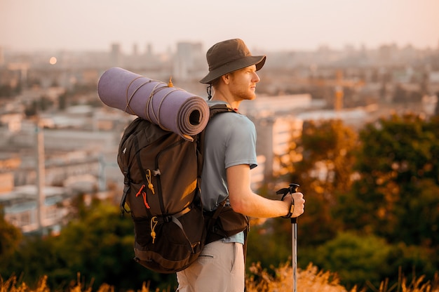 Sur la colline. Un grand homme avec un sac à dos debout au sommet de la colline