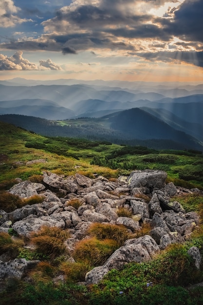 Colline de montagne avec ciel orageux et rayon de soleil au coucher du soleil